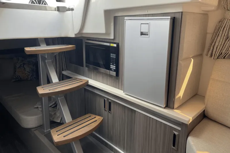 Slide: The Image of 2024 Sea Ray Sundancer 320 Outboard interior with stairs, microwave, and compact fridge. - 30