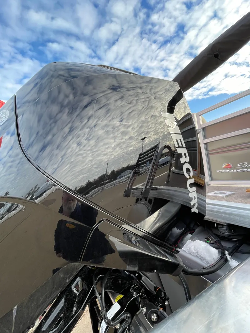 Slide: The Image of 2024 Sun Tracker Party Barge 22 XP3 with Mercury outboard motor under a cloudy sky. - 2