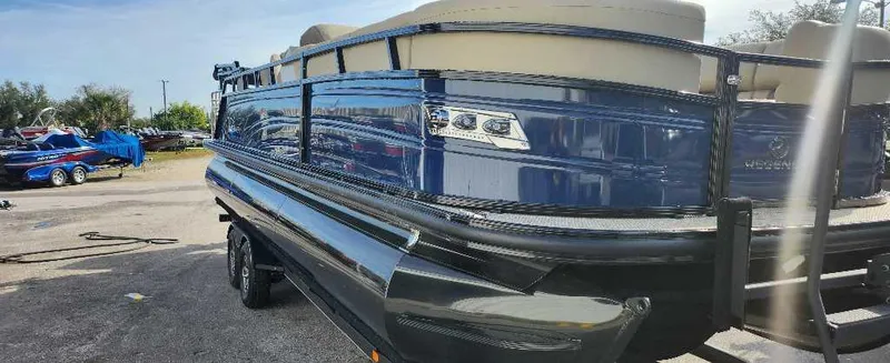 Slide: The Image of 2024 Regency 250 LE3 Sport pontoon boat in a parking lot. - 0