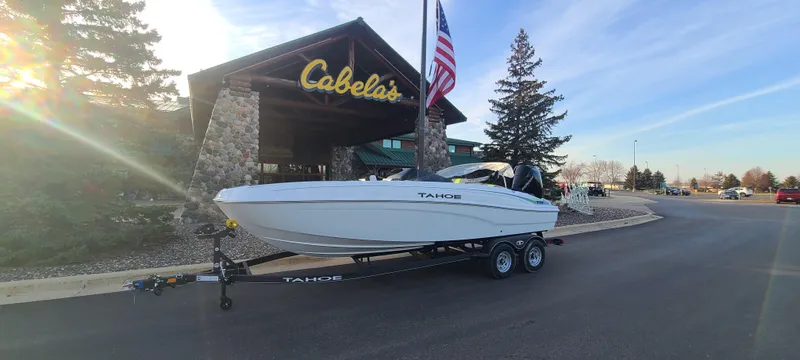 The Image of 2024 Tahoe T21 boat on trailer outside Cabela's store with American flag. - 0