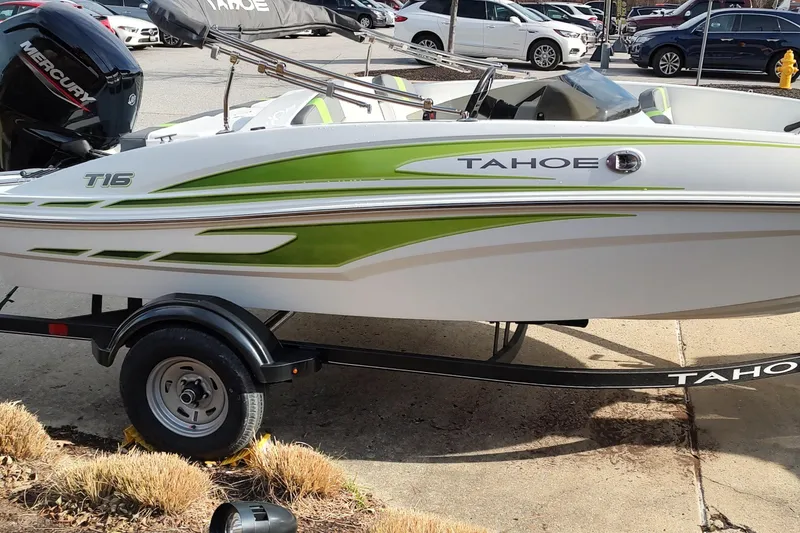 Slide: The Image of 2024 Tahoe T16 boat with green accents on a trailer, parked outdoors. - 2