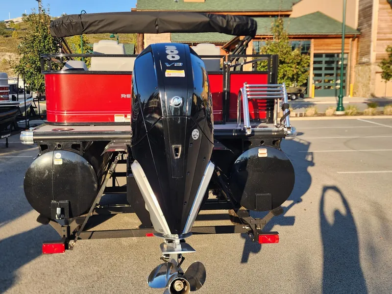 Slide: The Image of 2024 Regency 250 DL3 pontoon boat with powerful outboard motor in a parking lot. - 3