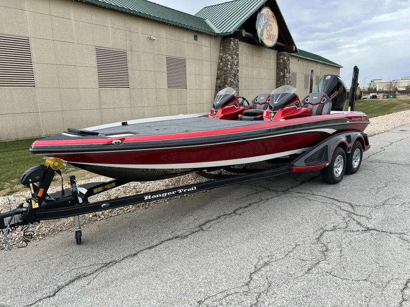 Slide: The Image of 2024 Ranger Z521R bass boat in red on a trailer, parked outside a building. - 1