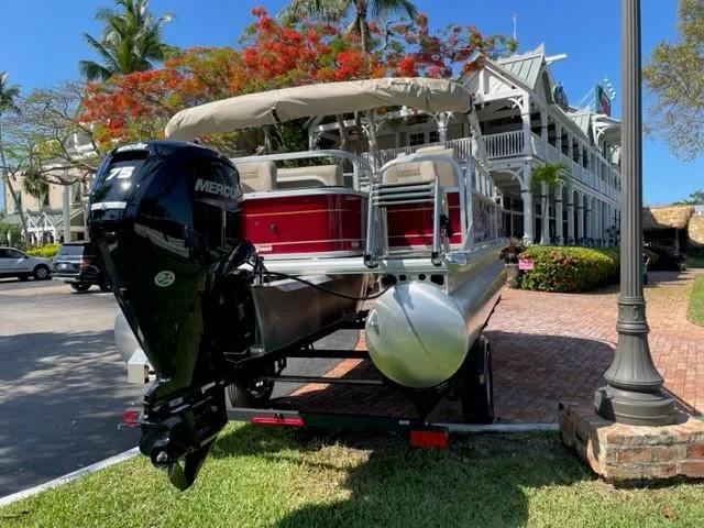 Slide: The Image of 2024 Sun Tracker Bass Buggy 18 DLX pontoon boat with Mercury 75 engine, parked near a building. - 3