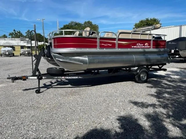 Slide: The Image of 2024 Sun Tracker Bass Buggy 18 DLX pontoon boat on trailer in outdoor lot. - 4