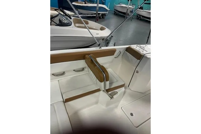 Slide: The Image of 2021 Bayliner DX 2200 boat interior with tan and white seating in showroom. - 11