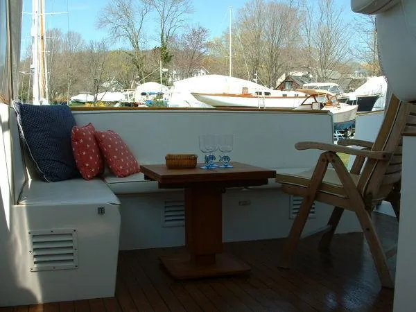 Slide: The Image of 1972 Huckins Atlantic 50 yacht deck with seating, table, and scenic marina view. - 8