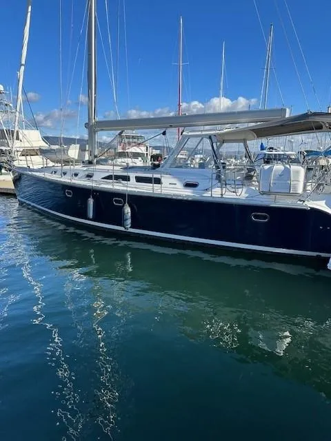 Slide: The Image of 2009 Catalina 470 sailboat docked in marina, reflecting on calm water under clear blue sky. - 4