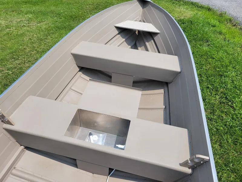 Slide: The Image of 2025 Smoker Craft 16 Voyager tiller boat interior, beige seating, grassy background. - 6