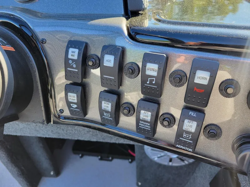 Slide: The Image of Control panel of 2024 Smoker Craft Ultima 172 boat with various switches and buttons. - 21