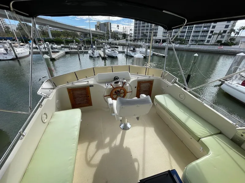 Slide: The Image of 1988 Kha Shing 40 Sundeck yacht's upper deck with helm, seating, and marina view. - 13