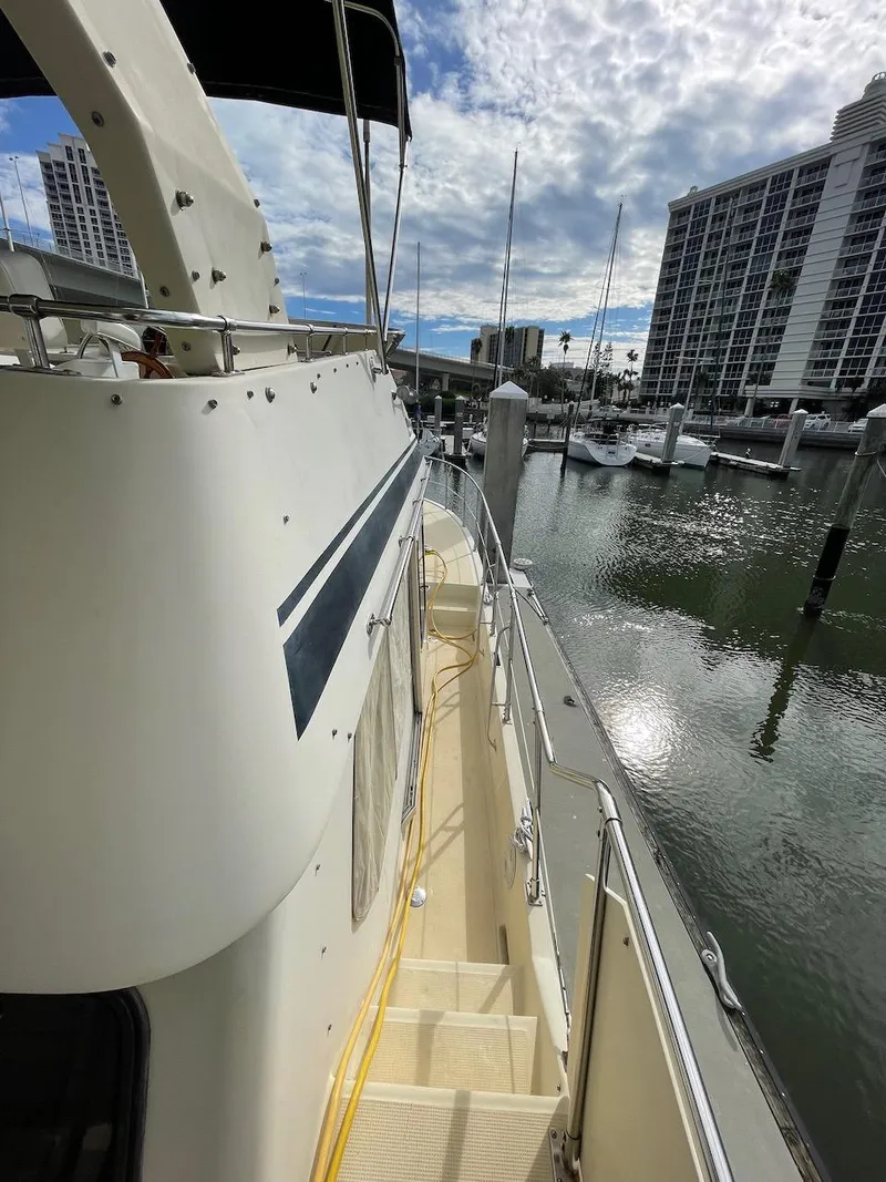 Slide: The Image of 1988 Kha Shing 40 Sundeck yacht docked at a marina with cityscape background. - 18
