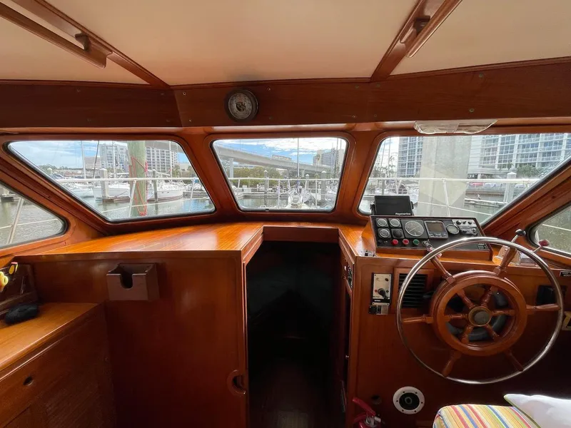 Slide: The Image of 1988 Kha Shing 40 Sundeck yacht helm with wooden steering wheel and marina view. - 32