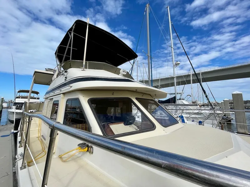 Slide: The Image of 1988 Kha Shing 40 Sundeck yacht docked at marina under blue sky. - 7