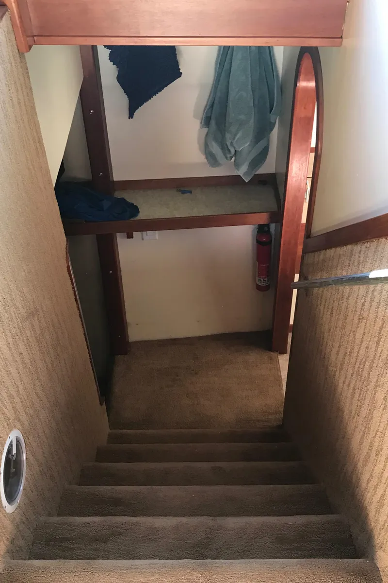 Slide: The Image of Staircase inside a 2008 Custom 62 Catamaran with carpeted steps and hanging clothes. - 18