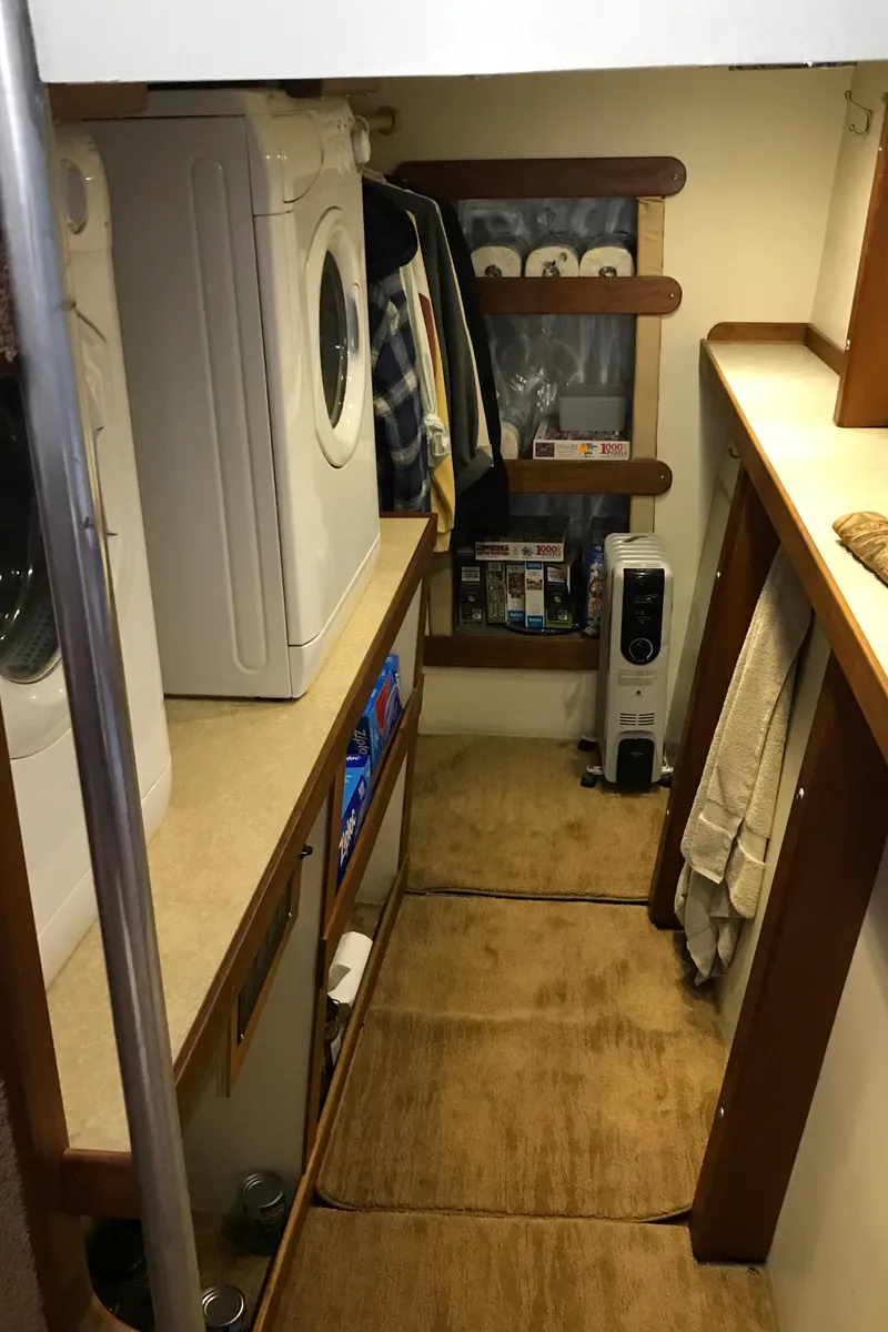 Slide: The Image of Laundry area inside 2008 Custom 62 Catamaran with washer, storage, and wooden accents. - 19