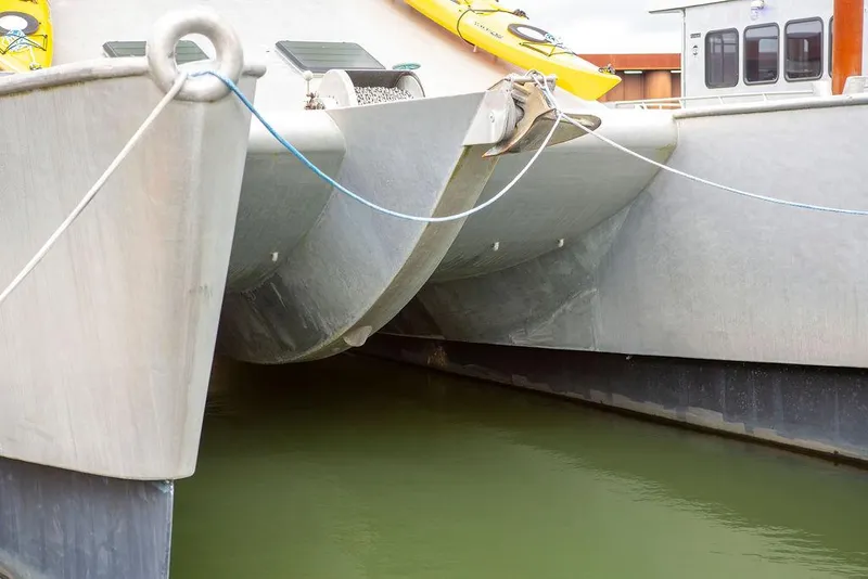 Slide: The Image of Custom 62 Catamaran 2008, docked with visible hulls and ropes, featuring yellow kayaks. - 44