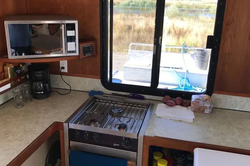 Slide: The Image of Kitchen area in a 2008 Custom 62 Catamaran with stove, microwave, and window view. - 7