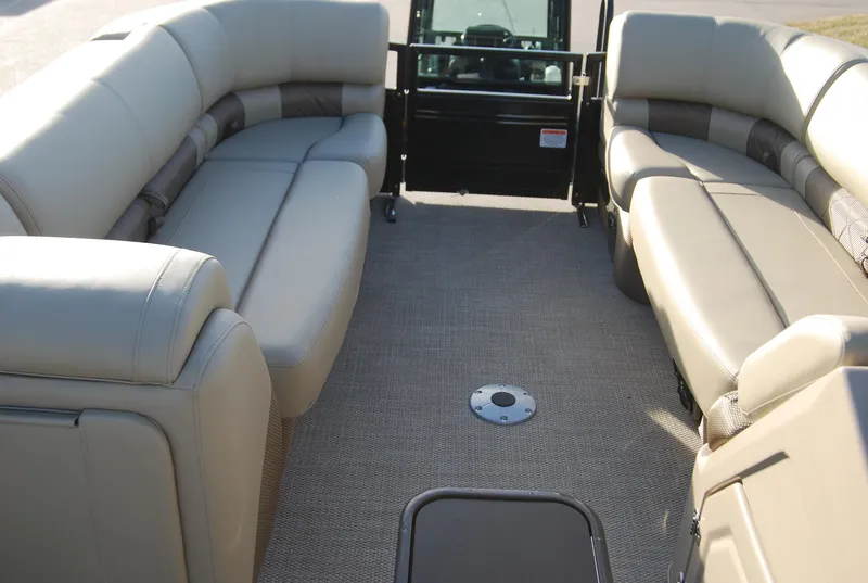 Slide: The Image of 2024 Regency 230 LE3 pontoon boat interior with beige seating and carpeted floor. - 7