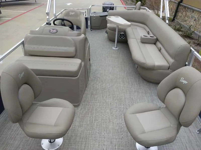 Slide: The Image of 2024 Ranger Reata 200F pontoon boat interior with beige seating and steering console. - 6