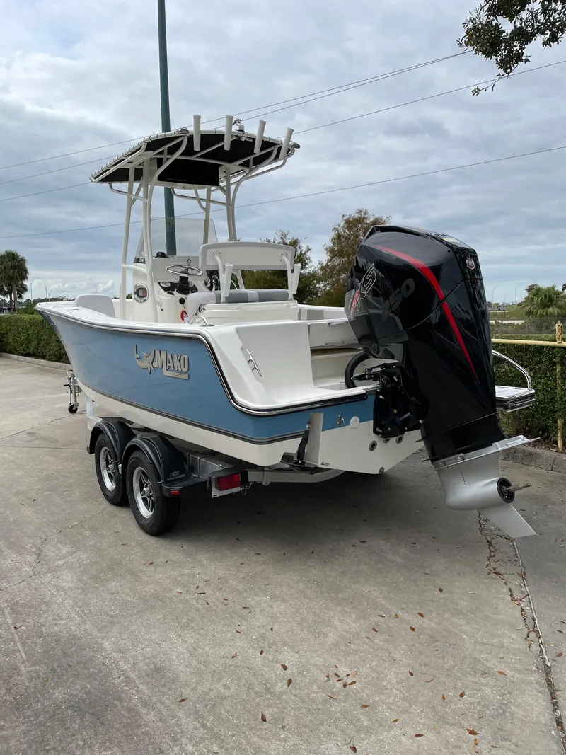 Slide: The Image of 2024 Mako 214 CC boat on trailer, featuring a powerful outboard motor. - 2