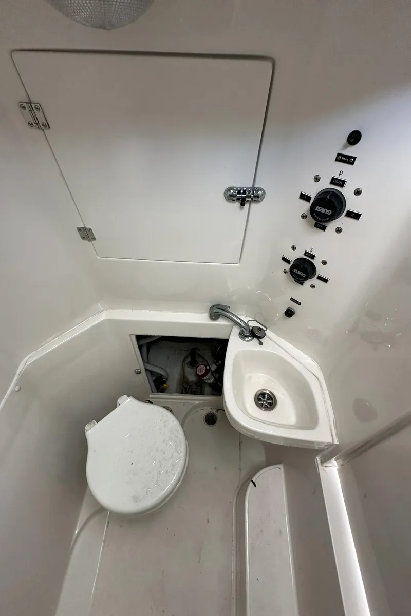 Slide: The Image of 2002 Jupiter 27 Open Fisherman boat bathroom with toilet, sink, and control panel. - 22