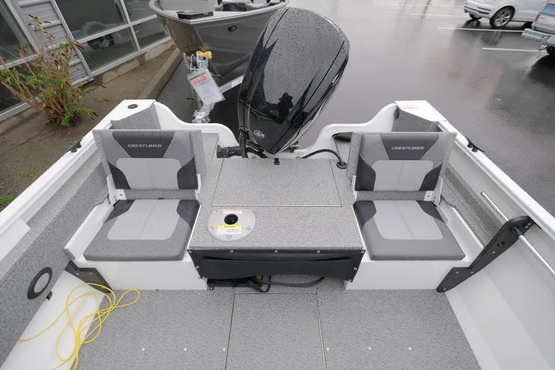 Slide: The Image of 2024 Crestliner 1600 Vision boat interior with seating and motor, parked outdoors. - 12