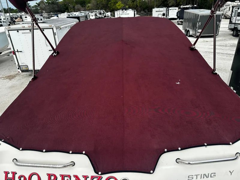 Slide: The Image of 2011 Stingray 250 LR boat with maroon cover in storage lot. - 10