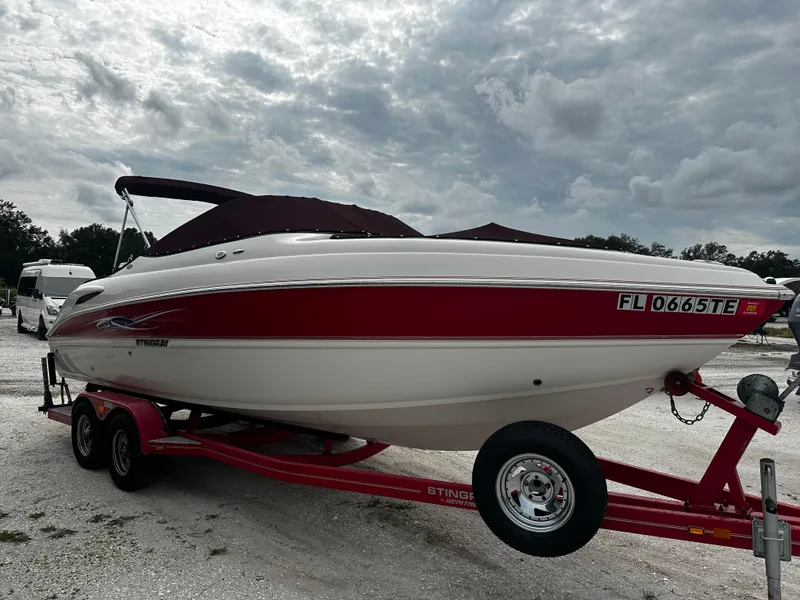 Slide: The Image of 2011 Stingray 250 LR boat on a red trailer, side view. - 2
