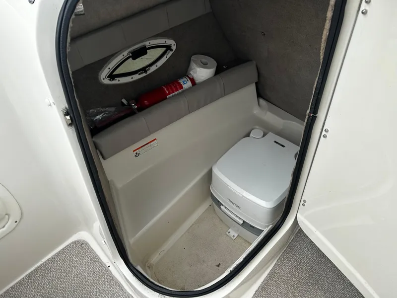 Slide: The Image of 2011 Stingray 250 LR boat cabin with portable toilet and fire extinguisher. - 24