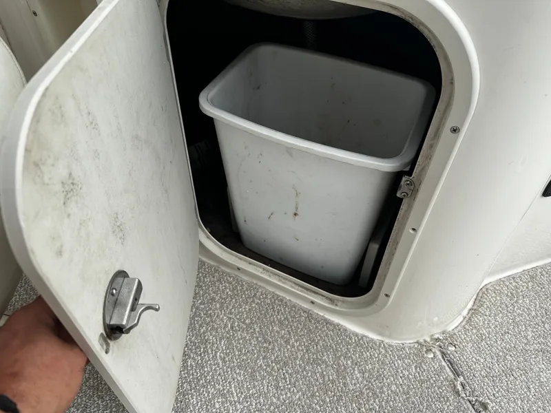 Slide: The Image of Storage compartment with a white bin on a 2011 Stingray 250 LR boat. - 28