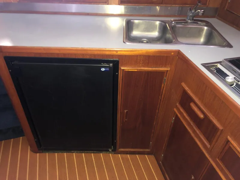 Slide: The Image of 1990 Mediterranean 38 Sport Fisher kitchen with wood cabinetry, sink, and compact refrigerator. - 12