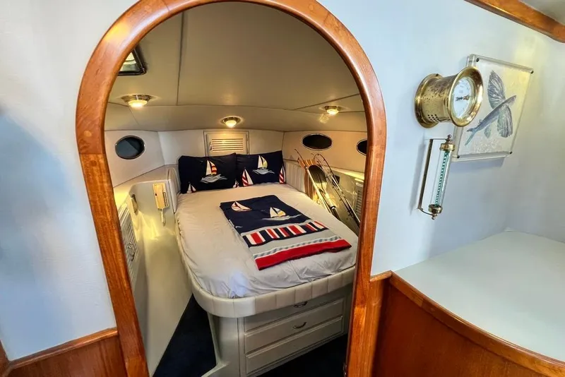 Slide: The Image of 1990 Mediterranean 38 Sport Fisher cabin with nautical-themed bedding and wooden accents. - 44