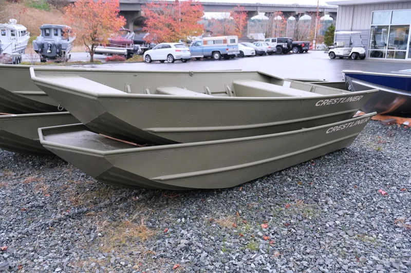 The Image of 2024 Crestliner 1448M CR Jon boats stacked outdoors in a dealership lot. - 1