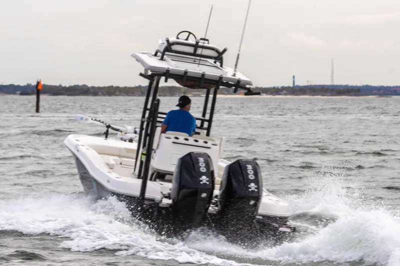 Slide: The Image of 2022 Caymas 281HB Center Console boat cruising on water with dual outboard engines. - 24