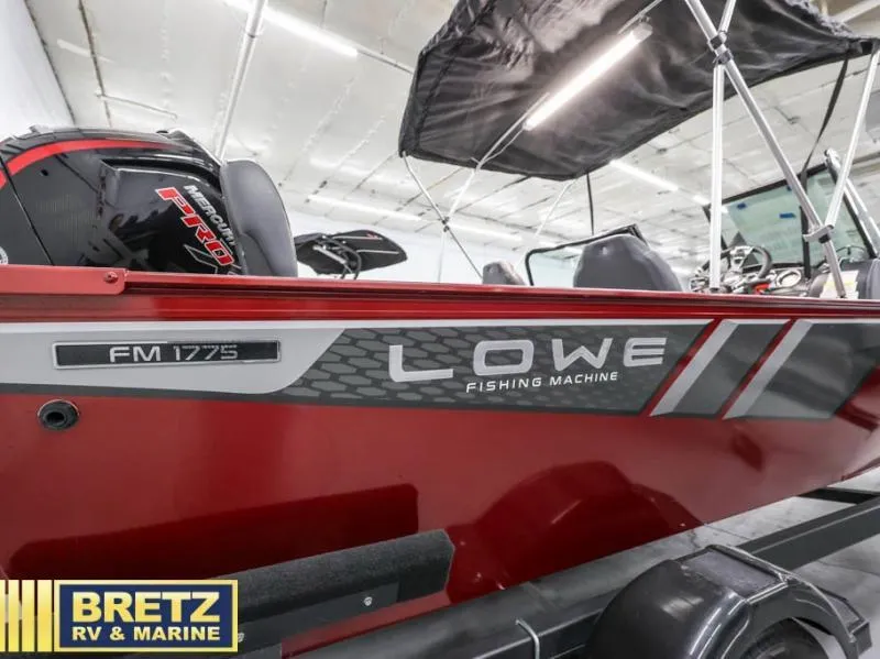 Slide: The Image of 2024 Lowe Fishing Machine 1775 WT boat in showroom, featuring sleek red design and canopy. - 11