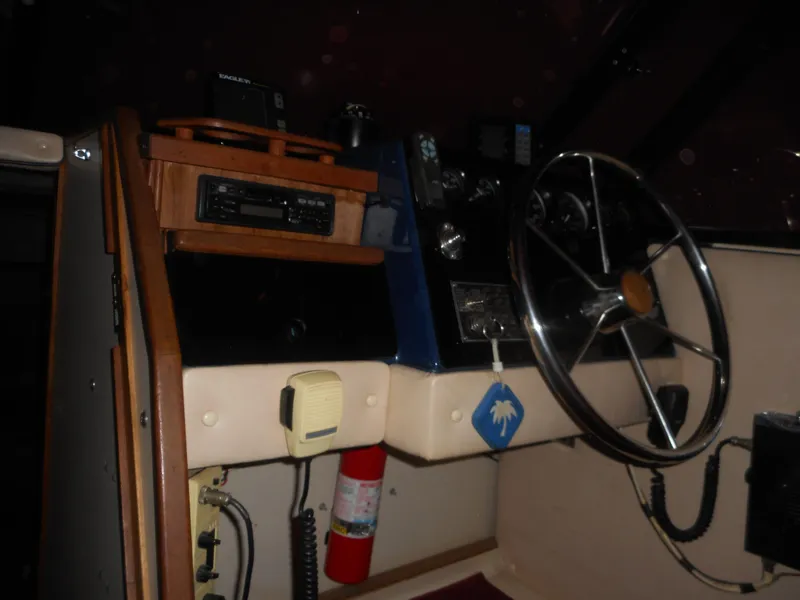 Slide: The Image of 1984 Beachcraft Cabin Cruiser helm with steering wheel, control panel, and fire extinguisher. - 10