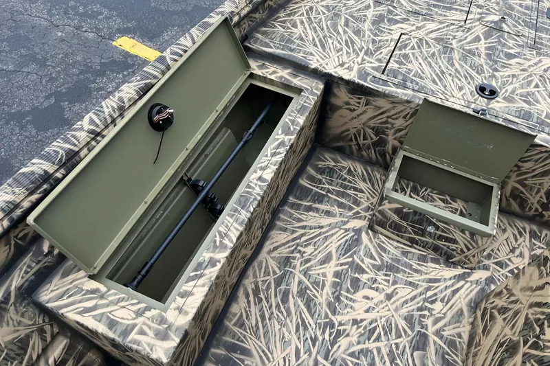 Slide: The Image of 2024 Lowe Roughneck RX1660 SC boat with open storage compartments and camouflage design. - 10