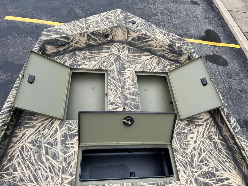 Slide: The Image of 2024 Lowe Roughneck RX1660 SC boat with open storage compartments and camouflage design. - 12