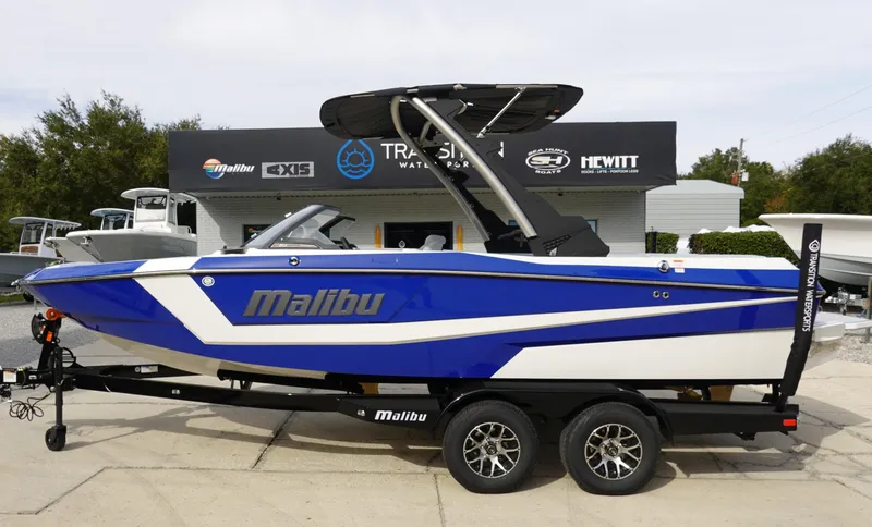 Slide: The Image of 2024 Malibu 21 LX-R boat in blue and white on a trailer. - 0