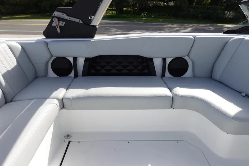 Slide: The Image of 2024 Malibu 21 LX-R boat interior with white cushioned seating and built-in speakers. - 16