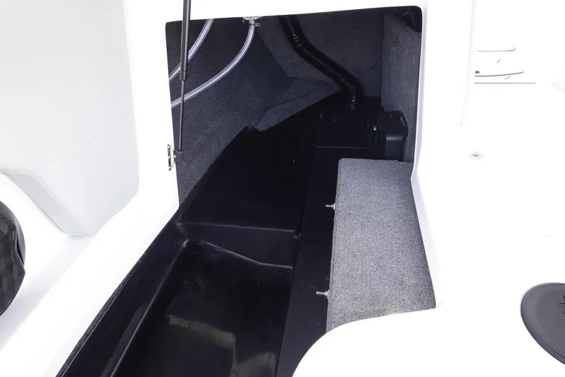 Slide: The Image of 2024 Malibu 21 LX-R boat storage compartment with black and grey interior. - 30