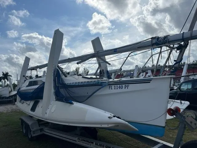 The Image of 1991 Corsair F27 sailboat on trailer under cloudy sky, ready for transport. - 1