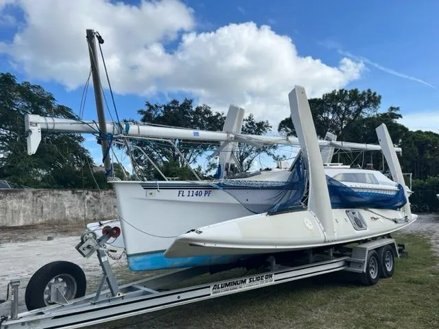 Slide: The Image of 1991 Corsair F27 sailboat on trailer, ready for transport under a partly cloudy sky. - 3