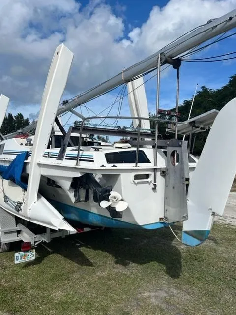 Slide: The Image of 1991 Corsair F27 sailboat on trailer, with folded amas, under a partly cloudy sky. - 5