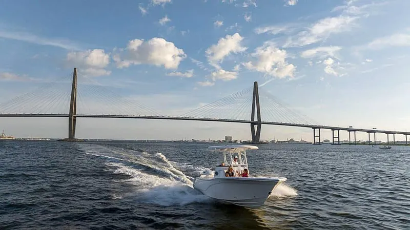 Slide: The Image of 2025 Sea Fox 248 Side Console boat cruising near a large suspension bridge. - 22