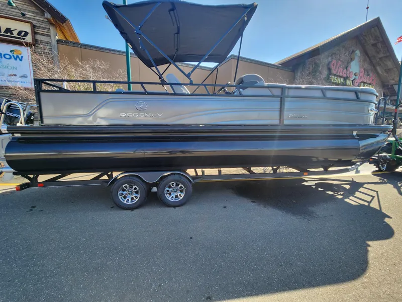 The Image of 2024 Regency 250 DL3 pontoon boat with black and silver exterior on a trailer. - 0