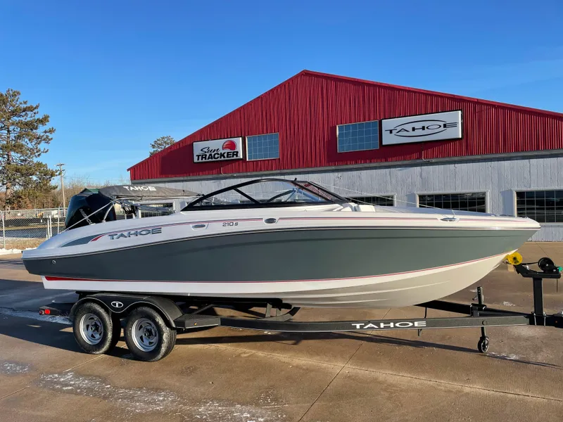 The Image of 2024 Tahoe 210 S boat on trailer in front of red building. - 1