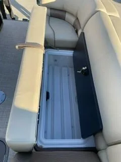 Slide: The Image of 2024 Regency 230 LE3 Sport boat with open storage compartment under beige seating. - 8