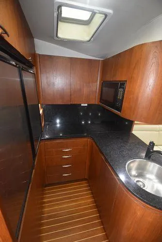 Slide: The Image of 1991 Tiara Yachts 4300 Open kitchen with wood cabinets and black countertops. - 38